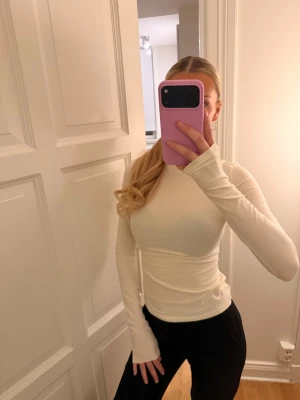 Vit långärmad topp från SKIMS - Säljer en stilren vit långärmad topp från SKIMS i mjuk bomull. Modellen är slim och har rund halsringning. Perfekt att styla med jeans eller kjol för en clean look. 