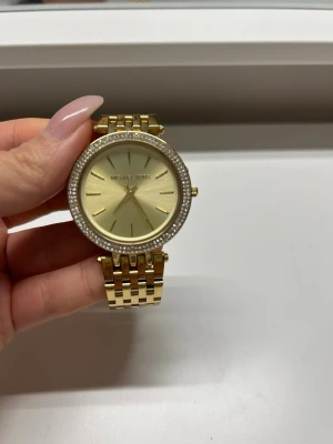 Michael kors klocka - Nästan oanvänd har bara legat i skåpet. OBS! Plast finns fortfarande på klockan underifrån, se bild 4. Behöver batteri, tyvärr finns varken förlängning eller låda kvar. Omkretsen 15cm