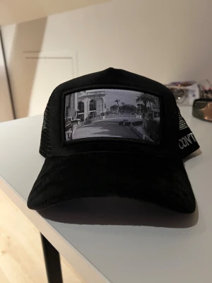 Svart velvet keps  - Säljer en svart velvet keps från CONTORE. Det är ett motiv med en bild från ett F1 Lopp i Monaco. Nypris: 699kr men här endast 479kr! 