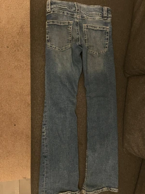 Blå bootcut jeans från Gina Tricot - Snygga blå jeans från Gina Tricot i storlek 152. Modellen har bootcut-ben och klassisk femficksdesign med kontrastsömmar. Jeansen har låg midja och är tillverkade i mjukt bomullsmaterial med lite stretch för skön passform.
