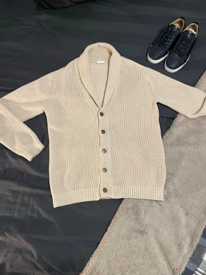 Beige kofta från John Henric - Tjenare! Säljer nu en beige cardigan från John Henric i väldigt fint skick. Det är en stickad modell med knäppning framtill och en stilren sjalkrage som ger ett mer uppklätt intryck. Klassisk och tidlös design som funkar lika bra till vardags som till mer dressade outfits. Passar perfekt som ett extra lager under vår och svalare sommarkvällar. Inga tydliga defekter, hel och fräsch. Jag är öppen för byten och kan mötas upp i Stockholm.
