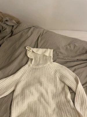 Vit stickad polotröja Gina Tricot - Säljer en vit stickad polotröja från Gina Tricot i storlek S. Tröjan har en hög krage och är långärmad med grovstickad struktur. Perfekt för kyliga dagar och enkel att matcha med jeans eller kjol.