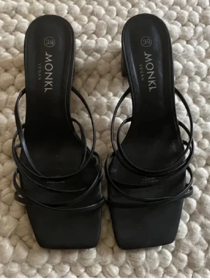 Svarta sandaler med smala remmar från Monki - Säljer ett par svarta sandaler från Monki med smala, minimalistiska remmar och fyrkantig tå. Skorna är veganska och har en stilren design som passar perfekt till sommarens outfits. Snygga att matcha med både jeans och klänning.