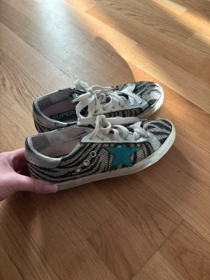 Golden goose superstars zebra mönster - Golden Goose superstar sneakers som är zebramönstrade med blå stjärna! Skorna är i bra skick och är i storlek 36