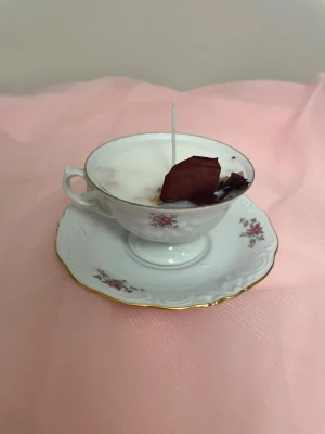 Vanilj doftljus i en vit tekopp med blommor  - Det här ljuset är gjort av återanvändbara material. Tekoppen är köpt secondhand och stearinet är från kyrkor som tänkte slänga det. Det här ljuset har en svag doft utav vanilj, så känsliga även kan använda det. Det här ljuset har även torkade blommor på som dekoration.