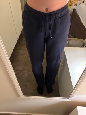 Mörkblå mjukisbyxor Gina Tricot XXS - Mörkblå mjukisbyxor från Gina Tricot, elevated basics-kollektionen. Byxorna har resår i midjan med snörning och raka ben. Tillverkade i mjukt material som är perfekt för chill dagar. Klassisk och enkel design utan tryck eller mönster.