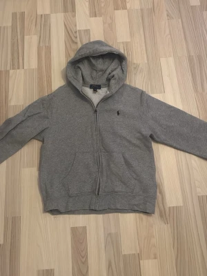 Ralph lauren hoodie - En grå ralph lauren hoodie med en mörkblå logga. Tröjan är i mycket bra skick och yeah