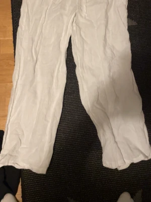 Vita linnebyxor med rak passform - Säljer ett par vita linnebyxor med rak och avslappnad passform. Perfekta för varma dagar och riktigt sköna att ha på sig. Byxorna har en enkel design utan synliga detaljer och är tillverkade i svalt linnematerial. Aldrig använda