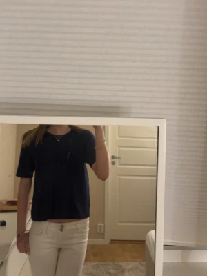 Mörkblå stickad topp från Nelly - Säljer en enkel och snygg mörkblå stickad topp från Nelly i storlek XS. Toppen har rund halsringning och korta ärmar, perfekt till jeans eller kjol. Materialet är mjukt och ger en avslappnad vibe.