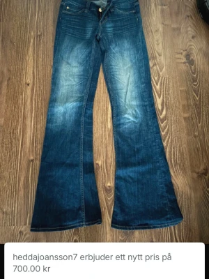 Blå bootcut jeans från Cheap Monday - Säljer ett par blå bootcut jeans från Cheap Monday med klassisk femficksmodell och orange logga bak. Jeansen har en snygg tvätt med slitningar framtill och är tillverkade i bomull med lite stretch för skön passform. Perfekta för dig som gillar retrovibbar och markerad siluett.