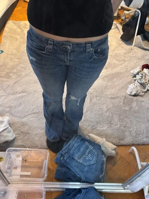 Blå bootcut jeans från Perfect Jeans - Säljer ett par blå bootcut jeans från Gina tricot i storlek 40 då dem blivit för stora. Jeansen har klassisk femficksdesign, snygga kontrastsömmar och en cool knappdetalj på bakfickan. Dem är i gott skick förutom att några av trådarna gått sönder vid hålen. Men de märks knappt i min åsikt. Pris kan diskuteras