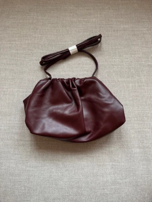 Vinröd clutch bag  - Säljer nu min superfina clutch bag då den inte kommer till användning. Denna passar både höst och sommar och har ett justerbart band så den passar alla. Bara att höra av sig vid eventuella frågor!