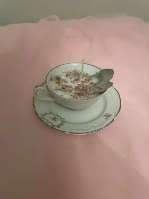 Doftljus i en vaniljdoft i en vit tekopp med blommor på nr 5 - Det här ljuset är gjort av återanvändbara material. Tekoppen är köpt secondhand och stearinet är från kyrkor som tänkte slänga det. Det här ljuset har en svag doft utav vanilj, så känsliga även kan använda det. Det här ljuset har även torkade blommor på som dekoration. Det finns fler av denna design på hemsidan om man vill köpa sets. 