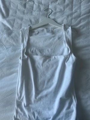 Vit linnetopp från Gina Tricot XS - Säljer en enkel och stilren vit linnetopp från Gina Tricot, kollektionen Elevated Basics. Toppen har breda axelband, rak halsringning och ärmlös design. Tillverkad i mjuk bomull som känns skön mot huden. Perfekt att matcha med jeans eller kjol.