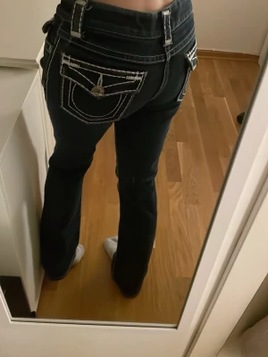 Mörkblåa Lowrised Jeans - Jättesnyggga mörkblåa jeans med tjock vit söm. Byxorna är Lowrised med raka ben. De är från The Shop Story, finns ingen lapp med storlek men skulle gissa på att de är S/XS. Ena knappen på en av bakfickorna är lite skadat som man kan se på sista bilden.  Hör av er vid frågor!