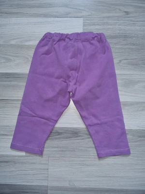 Lila 3/4 leggings från Polarn O. Pyret 122/128 - Säljer ett par lila 3/4 leggings från Polarn O. Pyret i mjuk bomull. De har resår i midjan och en liten etikett med logga på sidan. Perfekta för chill dagar eller till skolan. Färgen är riktigt härlig och materialet är skönt mot huden.