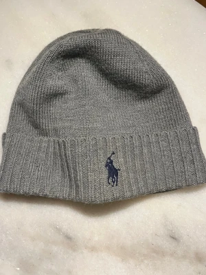 Grå polo Ralph Lauren mössa  - Grå polo Ralph Lauren mössa. Passar bra nu på vintern. Nästan helt ny och typ aldrig använt den. 