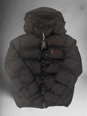 Black Ralph Lauren Jacket - Selling a brand new black Ralph Lauren jacket. It’s never been worn — only tried on, but unfortunately it was a bit too big for me. The jacket is in perfect, brand-new condition. High-quality and warm, making it ideal for winter. A clean, timeless design that easily matches any style, from casual to more dressed looks. Great opportunity to get a new Ralph Lauren jacket without paying full retail price. Its a little big in the size i think so ask me before for mesure so you dont get a jacket that