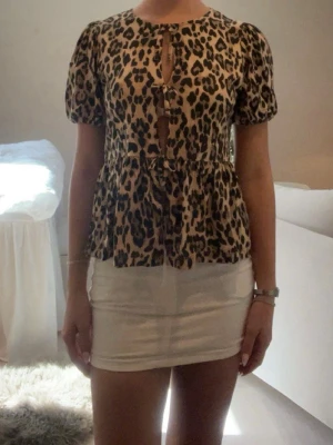 Leopardmönstrad blus med puffärm - Säljer en snygg blus med leopardmönster och puffiga korta ärmar. Toppen har volang nedtill och knytning .