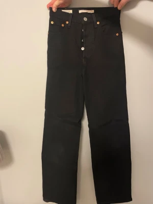 Svarta Levi's 501 jeans straight fit - Säljer ett par klassiska svarta Levi's 501 jeans med raka ben och hög midja. Jeansen är 90 cm långa från midjan och 30 cm midja till midja samt så är high waisted 25 cm men kan upplevas högre. Jeansen har knäppning framtill, fem fickor och den ikoniska läderlappen bak i midjan. Tillverkade i slitstarkt bomullsjeansmaterial. Perfekta för en clean och tidlös look. Fråga mig om ni har mer frågor 🤗