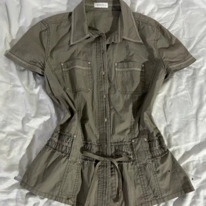 Camo grön tröja med knyt från Bonita - Aldrig använd. Fin kortärmad skjorta med knyte i midjan. Diskreta knappar och detalj baktill. Passar storlek s-M❤️