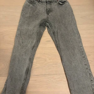 Grå jeansbyxor från Grunt, stl 27 - Snygga grå jeansbyxor från Grunt i klassisk rak modell. Byxorna har en cool tvättad look och normal passform. Perfekta för dig som gillar en avslappnad men ändå stilren vibe. Storlek W27 och är väl omhändertagna. Inga synliga tecken på användning.