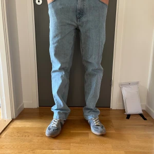 Wrangler ljusblå raka jeans - Ljusblå jeans från Wrangler med klassisk rak passform och tydliga W-detaljer på bakfickorna. Jeansen har normal midja och är tillverkade i robust denim. Perfekta för dig som gillar en avslappnad och tidlös stil. Köparen betalar frakt!