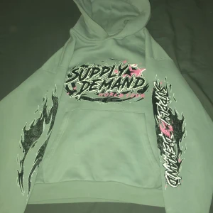 Grå hoodie Supply & Demand  - Grå hoodie från Supply & Demand med rosa och svarta detaljer andvänd 1 gång 