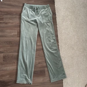 Gröna velourbyxor Juicy Couture S - Mysiga ljusgröna mjukisbyxor från Juicy Couture i velour med broderad JC-logga framtill, snörning i midjan och stora fickor både fram och bak. Perfekta för en chill och trendig look💚