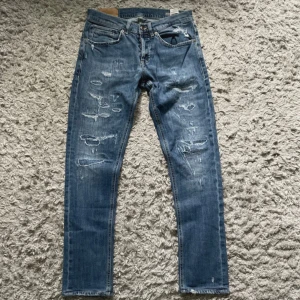 Blå Dondup jeans  - Säljer ett par blå skinny jeans från dondup med slitna detaljer och trasiga partier framtill. Jeansen har klassisk femficksdesign, normal midja och smal passform hela vägen ner. Perfekta för dig som är grisch och vill sticka ut. 
