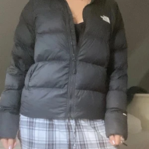 Svart dunjacka från The North Face M - Säljer en svart dunjacka från The North Face i storlek M. Jackan är puffer-modell med lång ärm, dragkedja framtill och klassisk logga på bröstet och ryggen. Perfekt för kalla dagar och har en stilren look inför vintern. Köpt för 2700kr säljer för 850kr