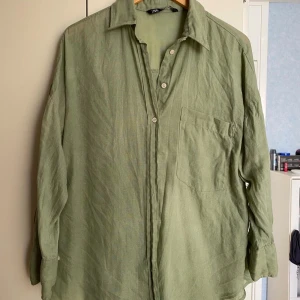 Grön linneskjorta från Zara - Snygg grön skjorta från Zara i 100% linne. Skjortan har klassisk krage, vita knappar framtill och en bröstficka. 