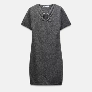 Grå stickad kortklänning från Zara - Mysig grå stickad kortklänning från Zara med korta ärmar och unik detalj vid halsringningen. Perfekt för lager-på-lager och enkel att styla med boots eller sneakers.