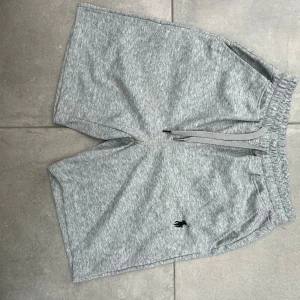 Grå shorts från Polo Ralph Lauren - Säljer Snygga grå shorts från Polo Ralph Lauren med klassisk broderad logga i svartsyn jag köpte på vinted men de var för stora. De har elastisk midja med snörning och är tillverkade i mjuk bomull. Perfekta för chill dagar och har en clean, sportig look. Skriv gärna om ni har frågor eller vill diskutera pris!