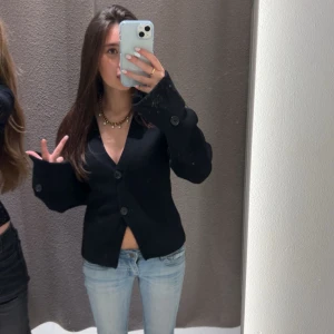 Populär cardigan från Gina med två knappar - Säljer min snygga svarta kofta 💞V-ringning och två knappar framtill. Modellen har långa ärmar med knappdetaljer vid ärmsluten. Perfekt inför hösten. Från Gina Tricot i storlek S, bara använd 2-3 gånger