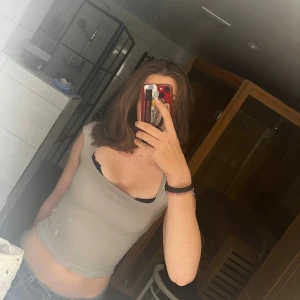 Ljusgrå croppad linnetopp - Säljer en ljusgrå croppad linnetopp med breda axelband och fyrkantig urringning. Toppen är figurnära och har en enkel, stilren design som passar perfekt till jeans eller kjol. Materialet känns mjukt och stretchigt.