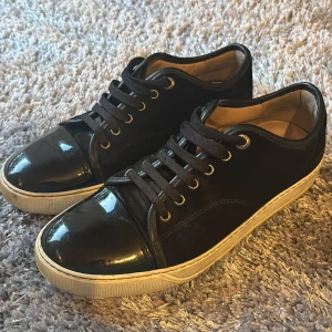 Lanvin skor - Snygga svarta sneakers från Lanvin med glansig tå och klassisk vit sula. Köpta på NK för ungefär 1 år sedan. Nya snörren, box, påse och kvitto ingår. Tveka inte att höra av dig vid fler frågor eller bilder.