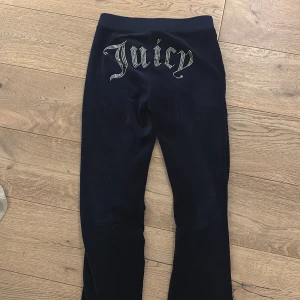 Juicy Couture mörkblå mjukisbyxor  - Mörkblå mjukisbyxor från Juicy Couture med glittrande stenar som bildar texten 'Juicy' på baksidan. Byxorna har snörning i midjan, fickor fram och är gjorda i mjuk sammet. Perfekta för en chill och trendig look. Pris går att diskutera🥰🥰