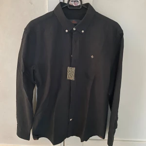 NY SKICK Morris skjorta i svart - Säljer en helt ny Morris skjorta i svart, storleken är M och modellen är ca 180cm lång. Hör av dig vid funderingar!