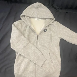 Cdg zip hoodie - Grå zip hoodie från cdg. Tröjan är använd 2-3 gånger men är i princip i ny skick. Tveka inte på att höra av er för fler bilder eller allmänna frågor 