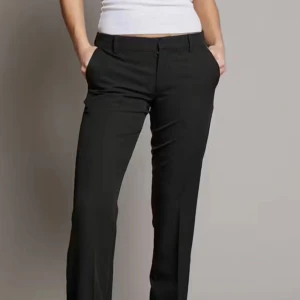 Svarta lågmidjade kostymbyxor - Snygga svarta VERA kostymbyxor från bikbok i normal passform. Perfekta för både kontoret och festliga tillfällen. De har en klassisk design men dragkedja och knappar. Byxorna är tillverkade i ett bekvämt material som ger en stilren look. Säljer då dom var för korta