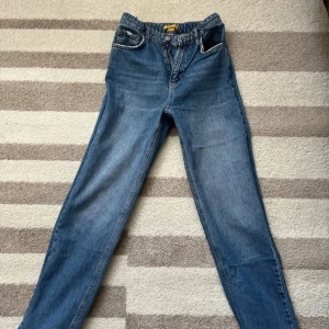 Gina tricot blå jeans straight fit - Gina tricot jeans i blå denim med rak passform och normal midja. Perfekta för dig som gillar tidlös stil och vill ha ett par jeans som funkar till allt.