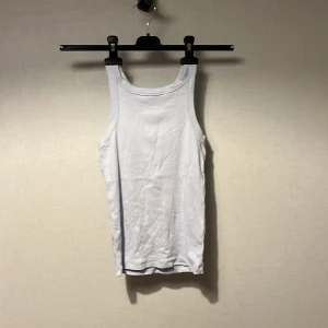 Vit linnetopp från Kappahl - Säljer en klassisk vit linnetopp från Kappahl i storlek 158/164. Toppen har rund halsringning och breda axelband, tillverkad i mjuk bomull med ribbade kanter. Perfekt för en chill och enkel stil under varma dagar.