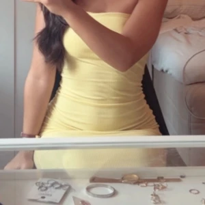 Gul ribbad tubklänning - Säljer en snygg gul tubklänning med ribbad struktur. Klänningen är kort och har en tight passform som framhäver figuren. Perfekt för dig som gillar färg och vill sticka ut. Ärmlös design som passar till varma dagar.