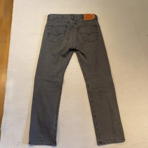 Grå Levi's 501 jeans W32 L32 - Säljer ett par klassiska grå Levi's 501 jeans med rak passform och femficksdesign. Jeansen är tillverkade i robust denim av bomull. Perfekta för dig som gillar en tidlös och avslappnad stil. Nästintill oanvända.