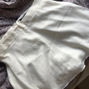 Vit satin-kortkjol från Forever 21 - Superfin vit kortkjol från Forever 21 i glansigt satinmaterial. Kjolen har en enkel och stilren design med dragkedja i sidan för en smidig passform. Perfekt för dig som gillar en clean och chic look.