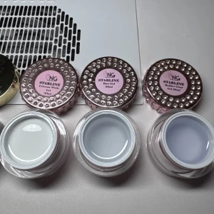 Starline gel för naglar 3-pack - Säljer tre burkar gel för naglar från NG Starline: Extreme White Gel, Base Gel och Builder Clear Gel, alla i 30 ml. Burkarna är rosa med pärldekor och har transparent, vit och klar gel för nagelförlängning och design.