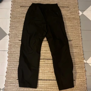 Överdrag byxor  - Svarta överdrag byxor med reglerings band i midjan. Reflex på botten och kardborre band för reglering.