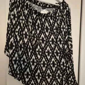 Svartvit mönstrad kjol Gina Tricot XL - Svartvit kjol från Gina Tricot i storlek XL med ett coolt grafiskt mönster. Kjolen är tillverkad i 100% viskos och har en avslappnad passform. Perfekt för dig som gillar statement-plagg med unik design.