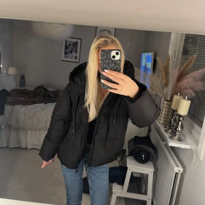 Svart pufferjacka från Zara XS - Svart pufferjacka från Zara i storlek XS. Jackan har en stor huva och dragkedja framtill och passar kalla dagar. Jackan är i väldigt fint skick. Bara att höra av dig vid frågor!💗